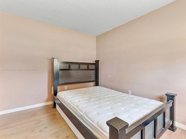 bedroom featuring light hardwood / wood-style flooring and a textured ceiling