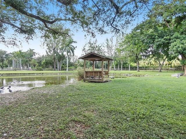 dock area with a gazebo, a water view, and a lawn