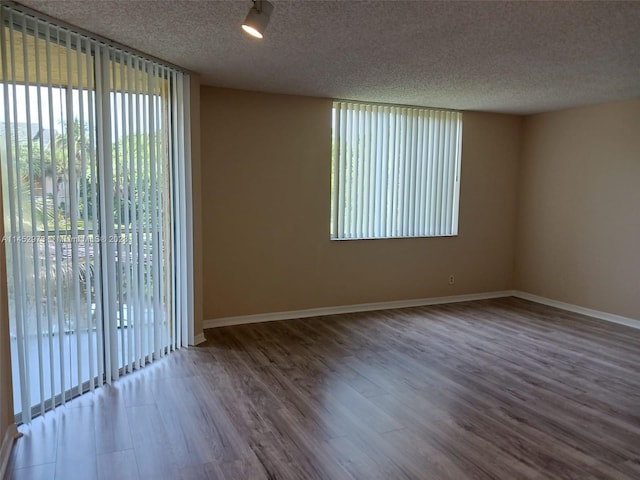 spare room with a textured ceiling and dark hardwood / wood-style floors