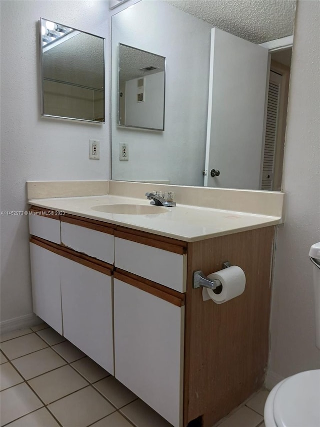 bathroom with oversized vanity, toilet, a textured ceiling, and tile floors