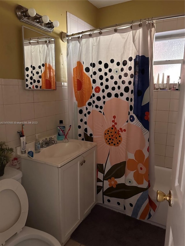 bathroom with toilet, vanity, and tile walls