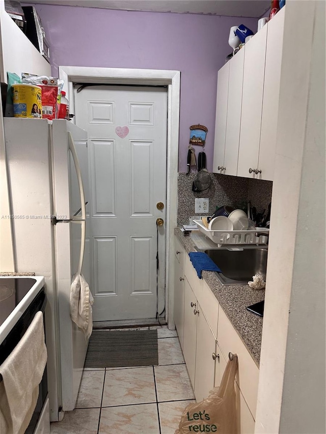 kitchen with light tile floors, white cabinets, and range with electric stovetop