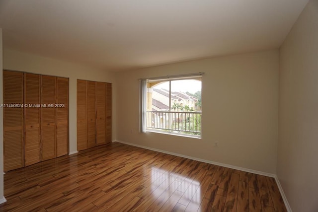 unfurnished bedroom with dark hardwood / wood-style floors and multiple closets