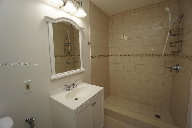 bathroom with toilet, a tile shower, and vanity