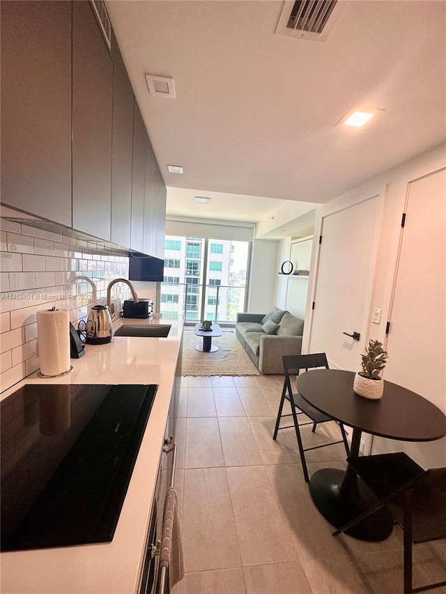 kitchen with sink, cooktop, tasteful backsplash, and light tile flooring