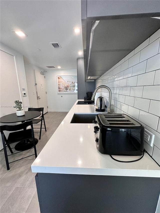 kitchen featuring light tile floors, tasteful backsplash, and sink