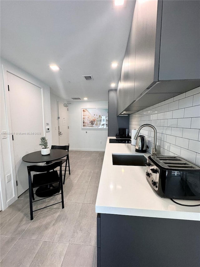 kitchen with backsplash, gray cabinetry, light tile flooring, and sink