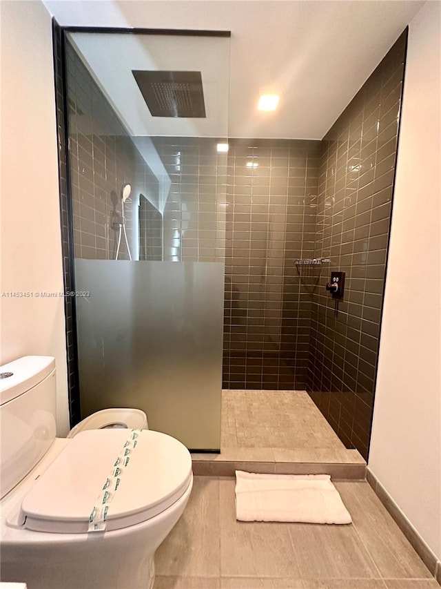 bathroom featuring toilet, tile flooring, and tiled shower