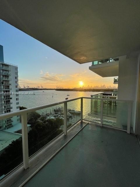 balcony at dusk featuring a water view