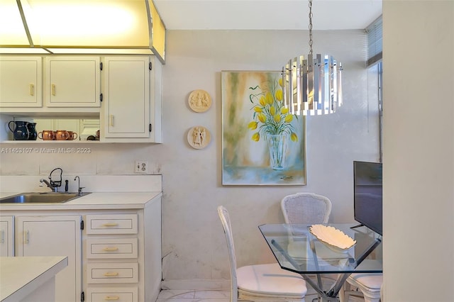 kitchen featuring sink, light tile floors, hanging light fixtures, white cabinets, and a chandelier