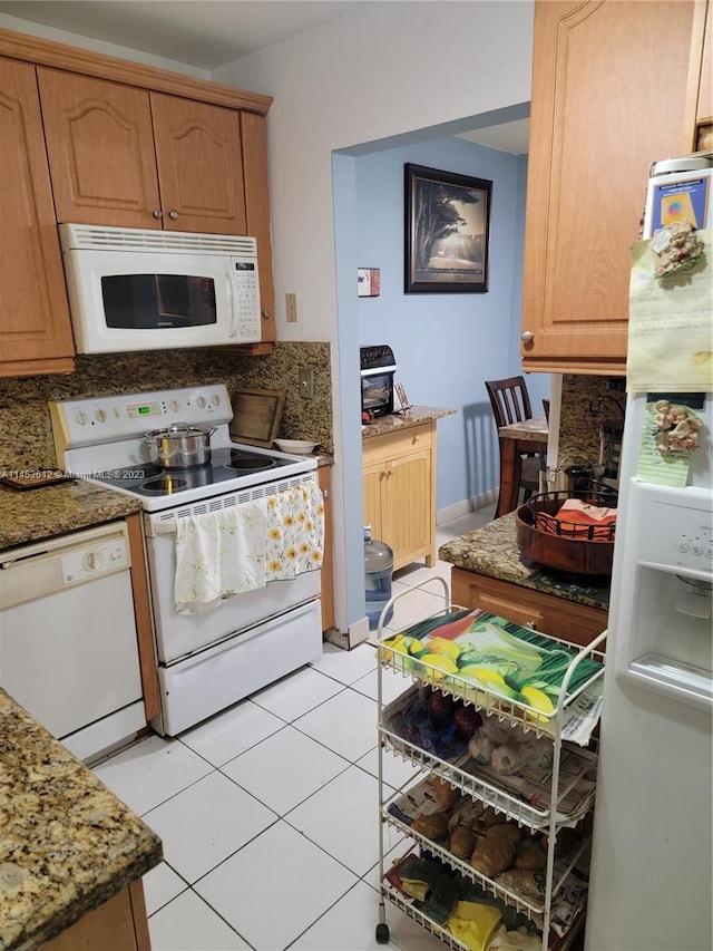 kitchen with tasteful backsplash, white appliances, stone countertops, and light tile floors