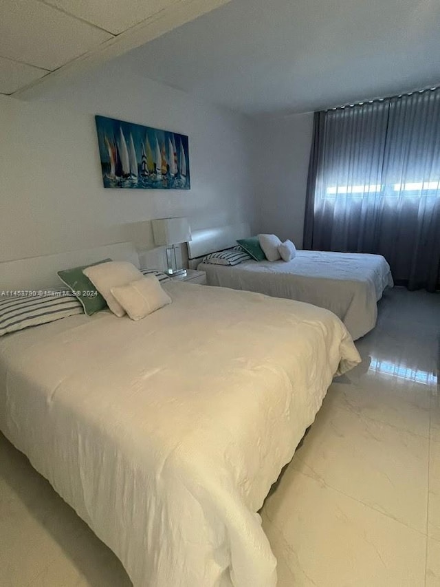 bedroom featuring a drop ceiling and light tile floors