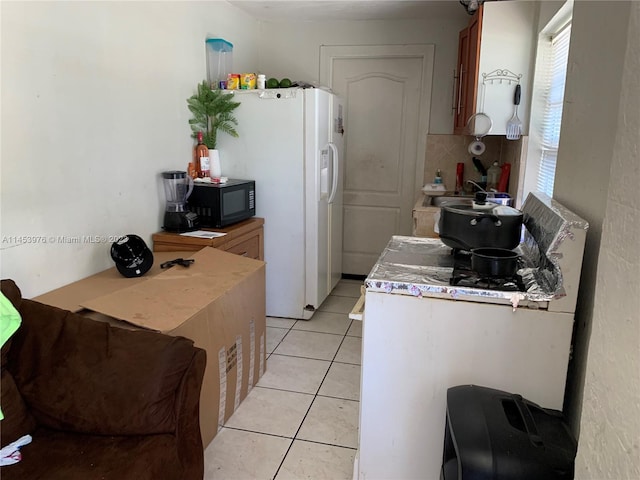 kitchen featuring light tile flooring, backsplash, and white fridge with ice dispenser