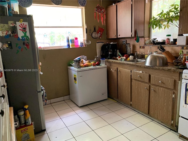 kitchen with tasteful backsplash, light tile flooring, and fridge