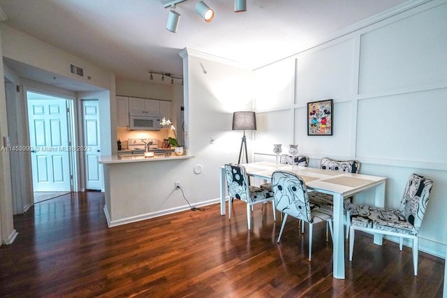 dining area featuring dark wood-type flooring and track lighting