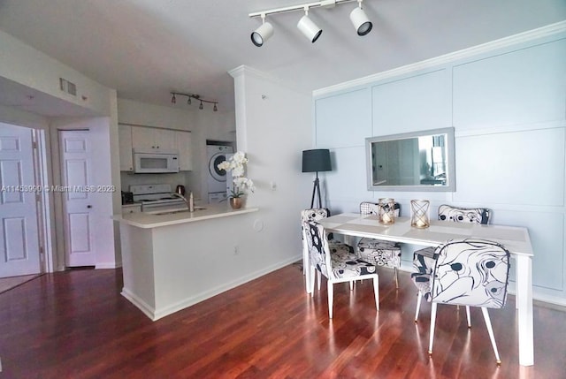 kitchen featuring kitchen peninsula, white cabinets, rail lighting, stove, and dark hardwood / wood-style flooring