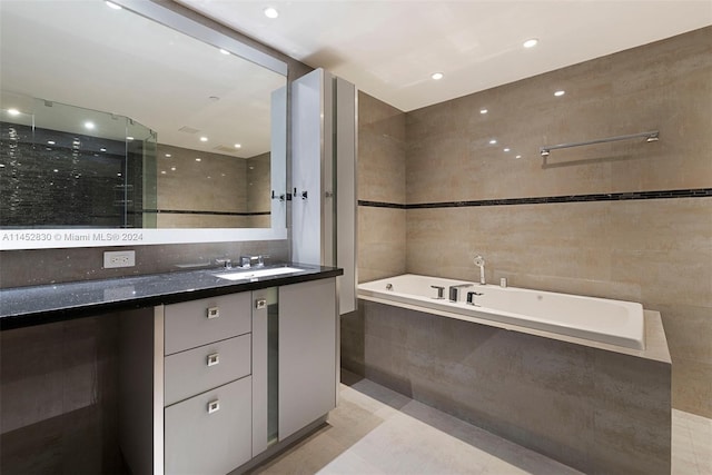 bathroom with a relaxing tiled bath, tile flooring, tile walls, and vanity