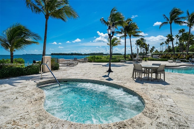 view of swimming pool with a water view and a hot tub