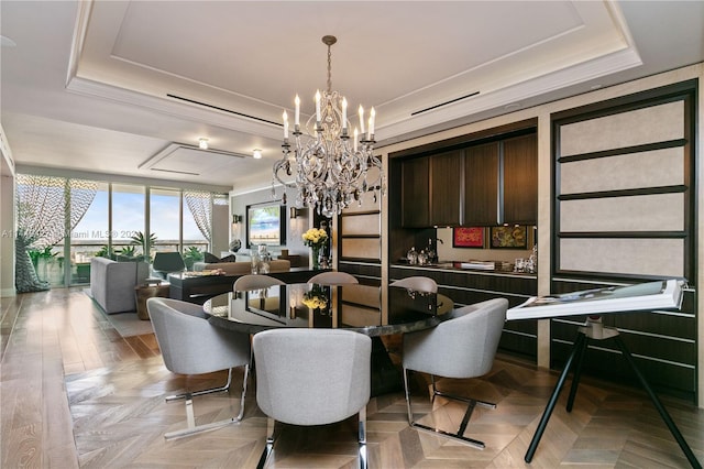 dining room with light parquet flooring, a raised ceiling, and a notable chandelier