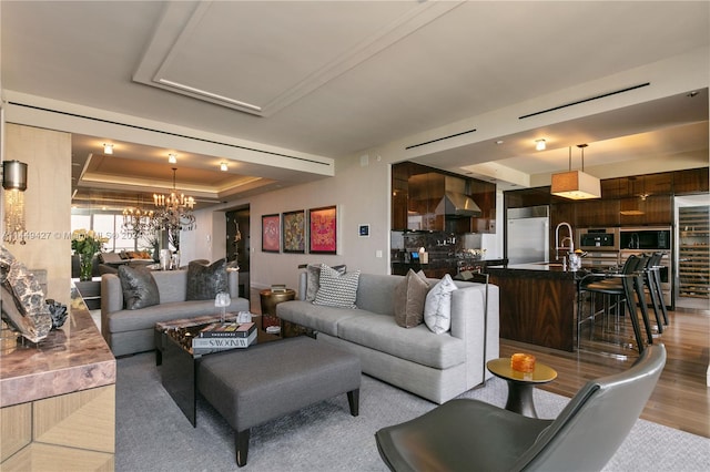 living room with a tray ceiling, hardwood / wood-style floors, and a chandelier