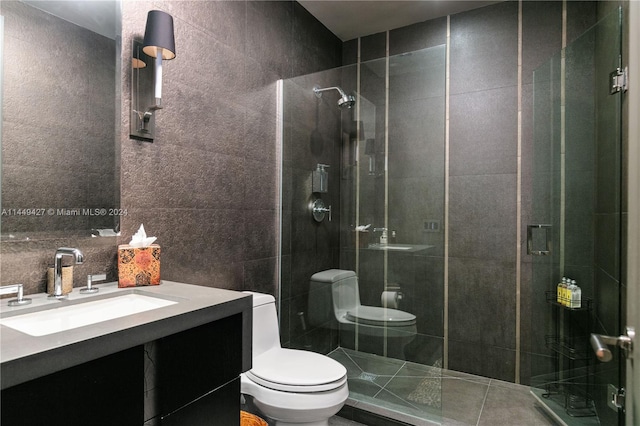 bathroom with tile walls, a shower with door, vanity, and toilet