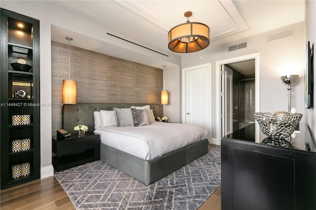 bedroom featuring ensuite bath and dark wood-type flooring