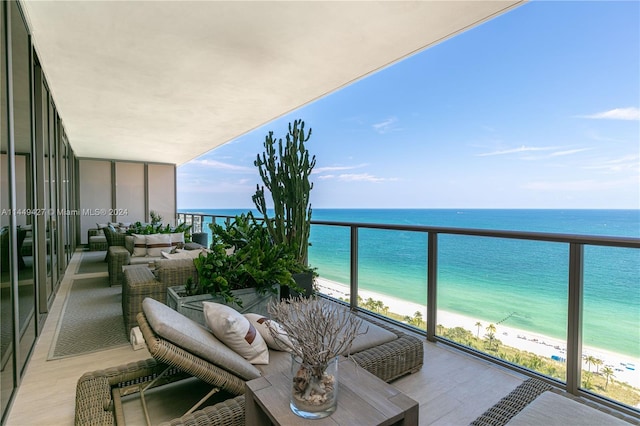 balcony featuring an outdoor living space, a water view, and a view of the beach