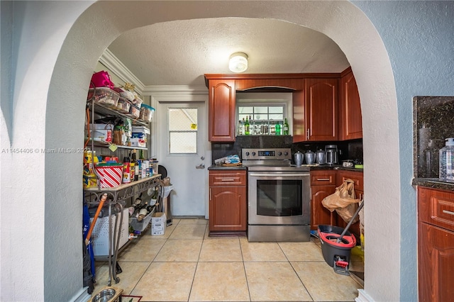 kitchen featuring stainless steel electric range, ornamental molding, backsplash, light tile flooring, and a textured ceiling