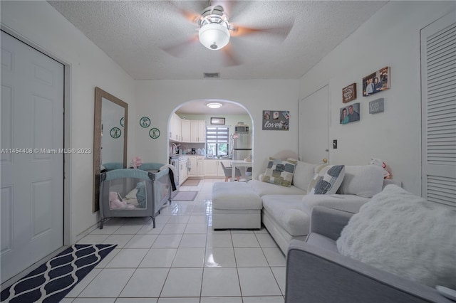 tiled living room with ceiling fan and a textured ceiling