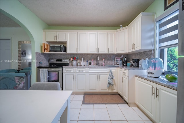 kitchen featuring white cabinetry, sink, stainless steel appliances, light tile floors, and tasteful backsplash