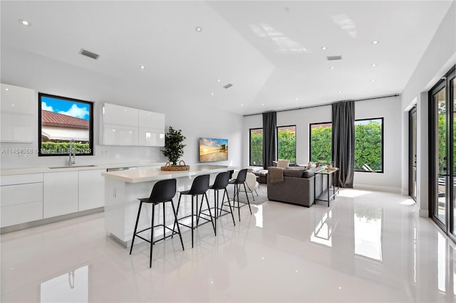 interior space with sink, light tile floors, a breakfast bar, white cabinetry, and a center island