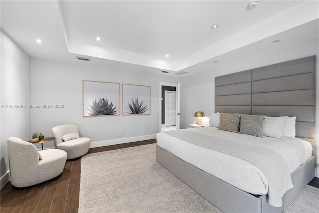 bedroom with a raised ceiling and dark wood-type flooring