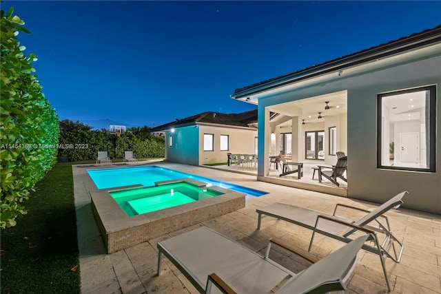 pool at twilight featuring a patio area and an in ground hot tub