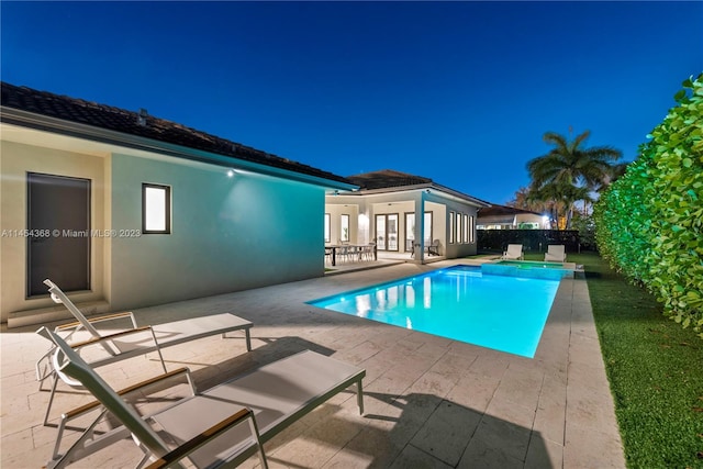 pool at twilight with french doors and a patio