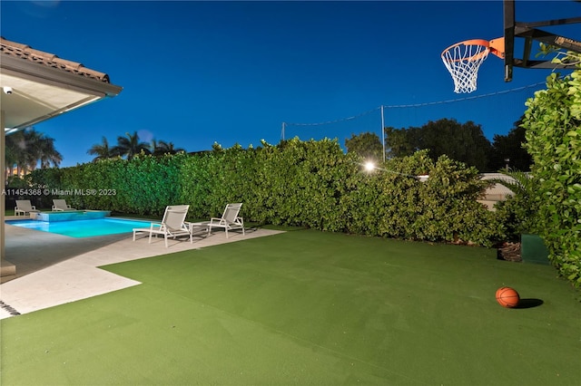 yard at night featuring a fenced in pool and a patio