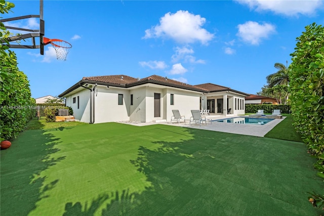 rear view of house featuring a yard, a patio area, and a fenced in pool