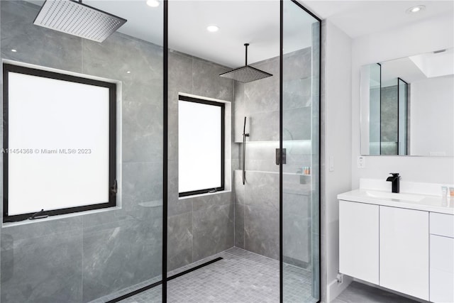 bathroom featuring a shower with shower door and vanity