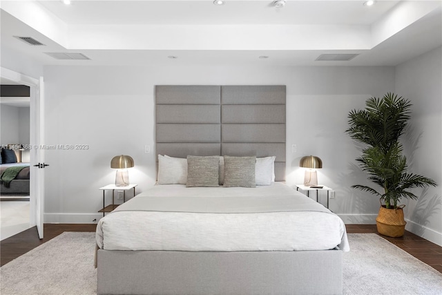 bedroom featuring a raised ceiling and dark wood-type flooring