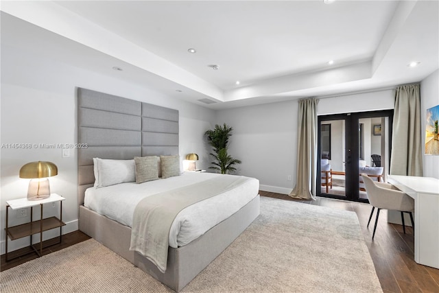 bedroom with french doors, a tray ceiling, and hardwood / wood-style flooring