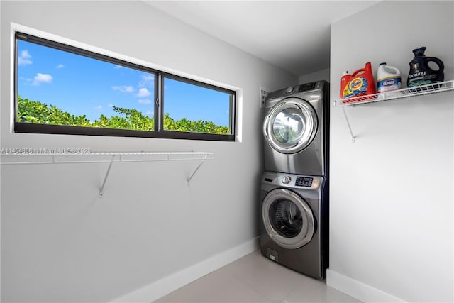 laundry area with stacked washer / drying machine and light tile flooring