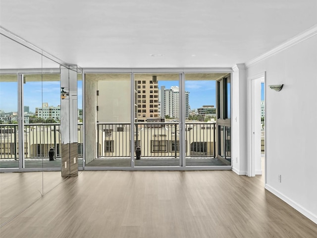 unfurnished room with crown molding, a wealth of natural light, and hardwood / wood-style floors