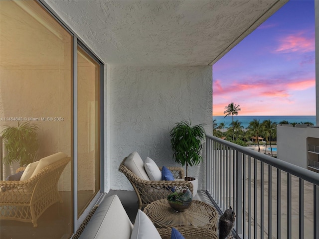 balcony at dusk featuring a water view