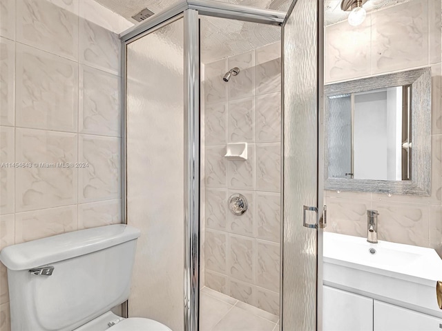 bathroom with toilet, an enclosed shower, vanity, a textured ceiling, and tile walls