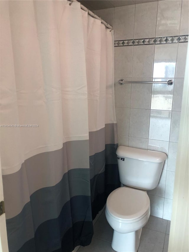 bathroom featuring tile patterned flooring, tile walls, toilet, and curtained shower