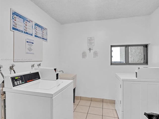 washroom with a textured ceiling, independent washer and dryer, and light tile patterned floors