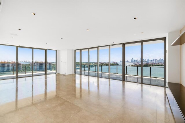 empty room featuring a water view, floor to ceiling windows, and light tile floors