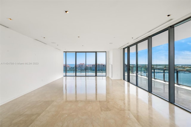 tiled spare room featuring a healthy amount of sunlight, expansive windows, and a water view