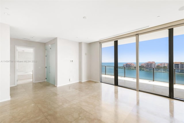 tiled spare room featuring floor to ceiling windows and a water view