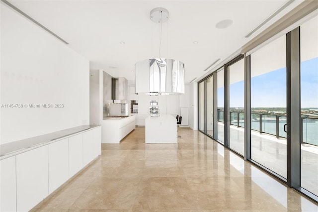 interior space with light tile floors, a wall of windows, and a water view