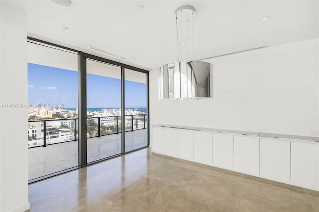 empty room featuring light tile flooring, a water view, and a wall of windows